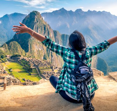 A woman tourist contemplating the amazing landscape of Machu Picchu with arms open